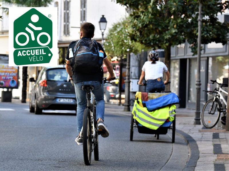 Cyclistes dans la rue Foch avec logo Label Accueil Vélo